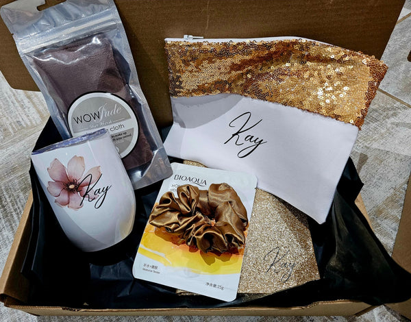 Gift box with a mug, snacks, and a pouch labeled 'Kay'.