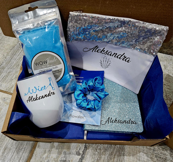 Box containing branded items including a mug, pouch, and other accessories with 'Aleksandra' branding.