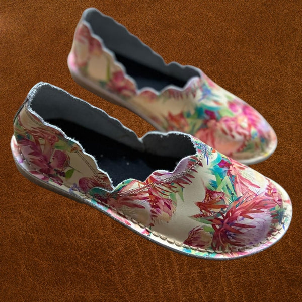 Floral-patterned shoes on a brown leather surface
